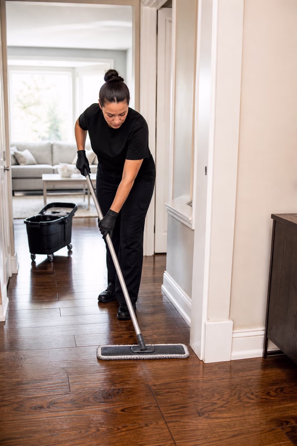 A cleaner polishing a hardwood floor and wiping baseboards during a residential deep clean in an Ottawa home.
