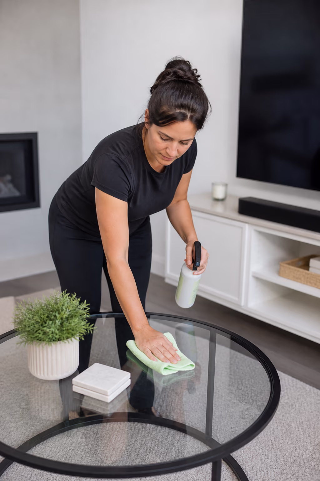 A cleaning technician resetting a tidy Ottawa living room, microfibre cloths and a labelled caddy at the ready for the recurring home clean.