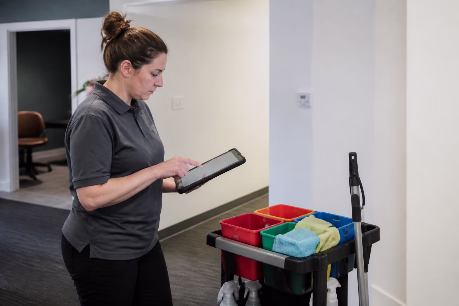 Cleaning technicians reviewing a digital cleaning checklist beside a colour-coded supply caddy before an after-hours commercial clean in Ottawa.