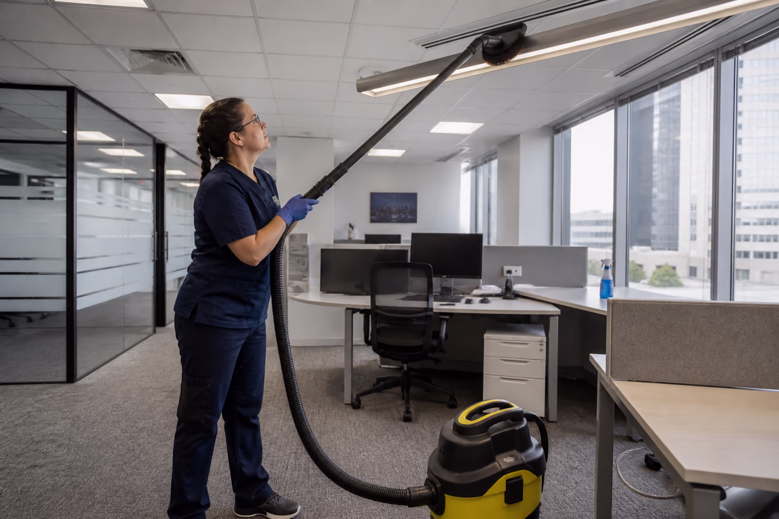 A cleaning technician reviewing a digital scope and access plan on a tablet outside an Ottawa office tower, with the downtown business district behind.