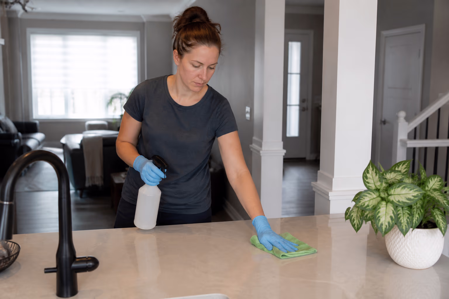 Two commercial cleaners in a bright Ottawa clinic disinfecting a reception counter, door handles and shared desks, with colour-coded microfibre cloths and a documented cleaning checklist nearby.