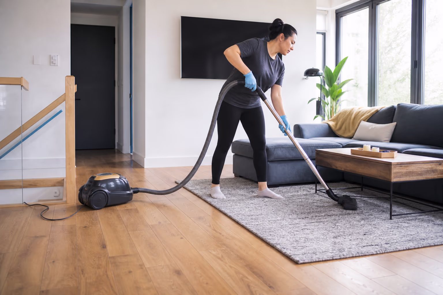 A landscape view of the team in matching uniforms working through a bright Ottawa living room, vacuuming and wiping surfaces on a scheduled housekeeping visit.