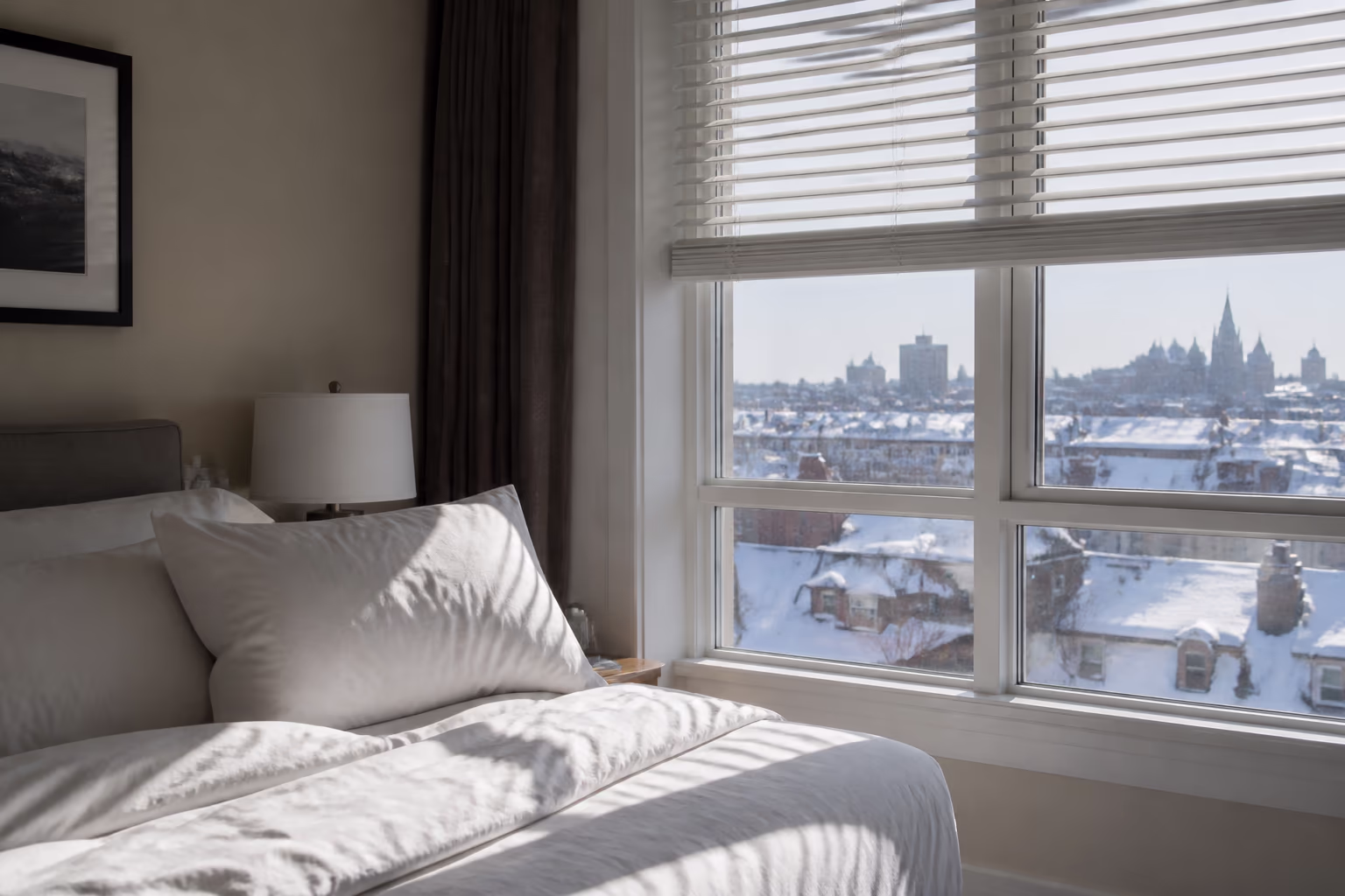 A bright Ottawa bedroom with fresh white linens beside a sunlit window, showing how the season's dust, furnace heat and humidity change how often bedding, blinds and kitchen cloths need cleaning.