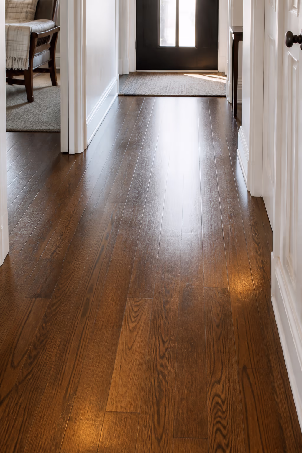 A well-maintained hardwood hallway in an Ottawa home with a soft shine, an entry mat at the door and a clean, sealed finish ready for the seasons.