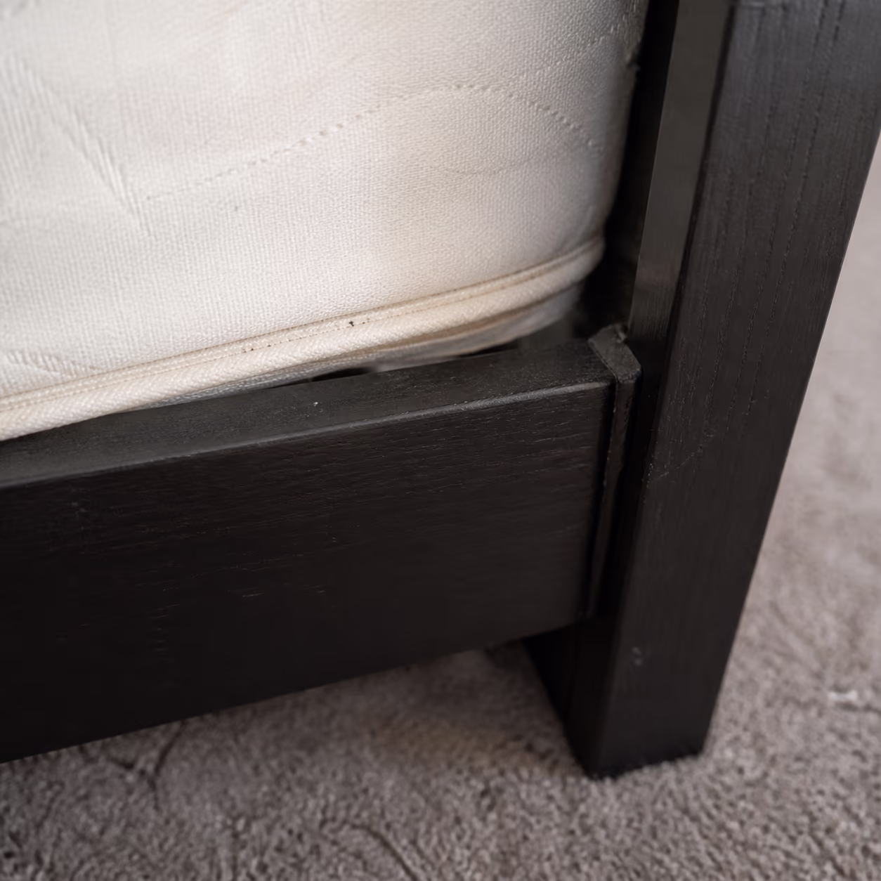 A square close-up of a bed frame corner and mattress seam in an Ottawa bedroom, the narrow gaps where bed bugs hide and the reason early containment stops them spreading one room at a time.