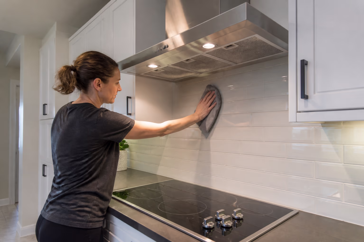 A wide view of a freshly degreased Ottawa kitchen: the range hood filter rinsed clean, the cooktop and backsplash wiped down, and the cabinet fronts and floor restored after a top-to-bottom heavy grease removal deep clean.