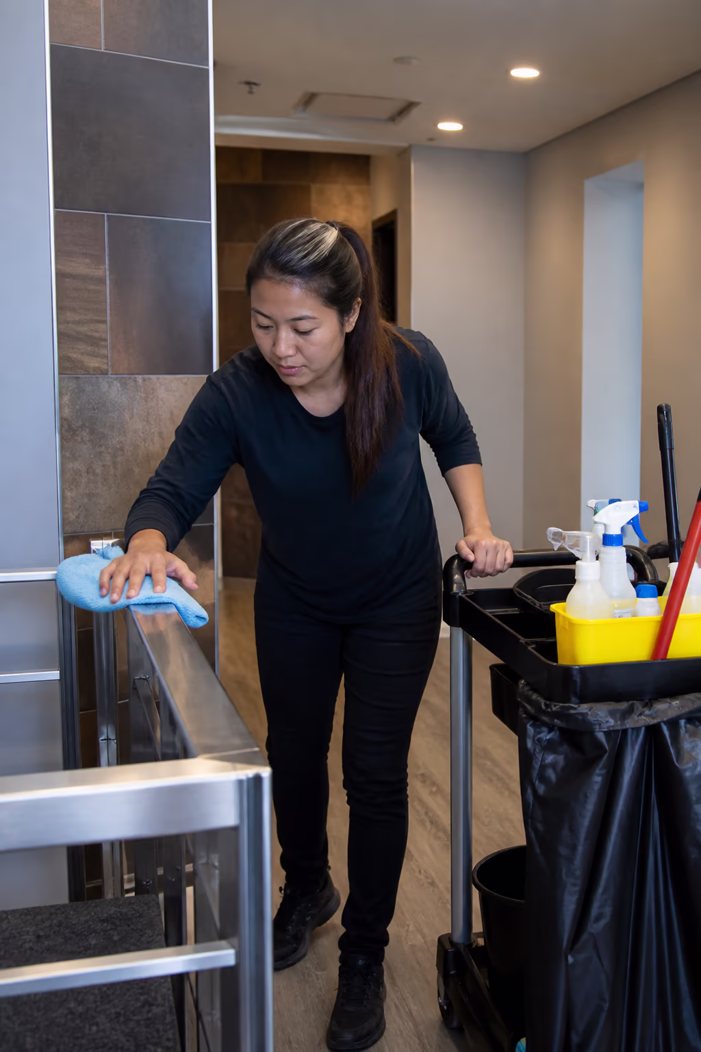 A portrait of a janitorial supervisor reviewing a printed training manual and sign-off sheets at an office desk in Ottawa, a binder of module checklists open beside a cleaning supply cart.