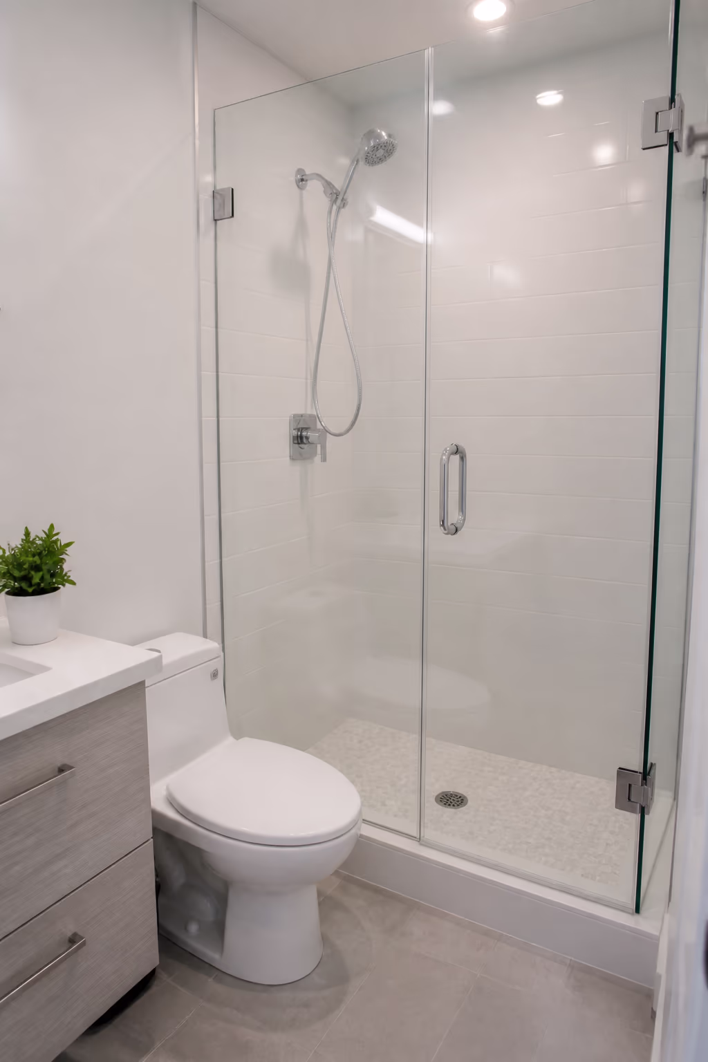 A portrait of a bright, freshly cleaned Ottawa bathroom with a clear glass shower door, gleaming chrome fixtures and grout that shows no hard water scale build-up.