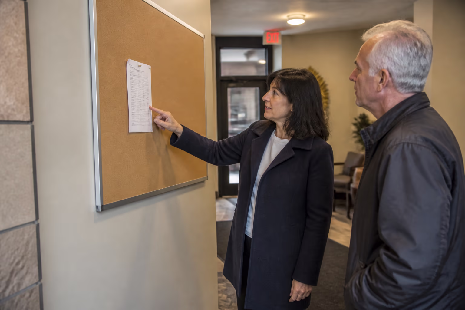 A portrait of a property manager sharing the cleaning schedule with tenants beside a notice board in an Ottawa building lobby, capturing the clear communication that keeps everyone working from the same plan.