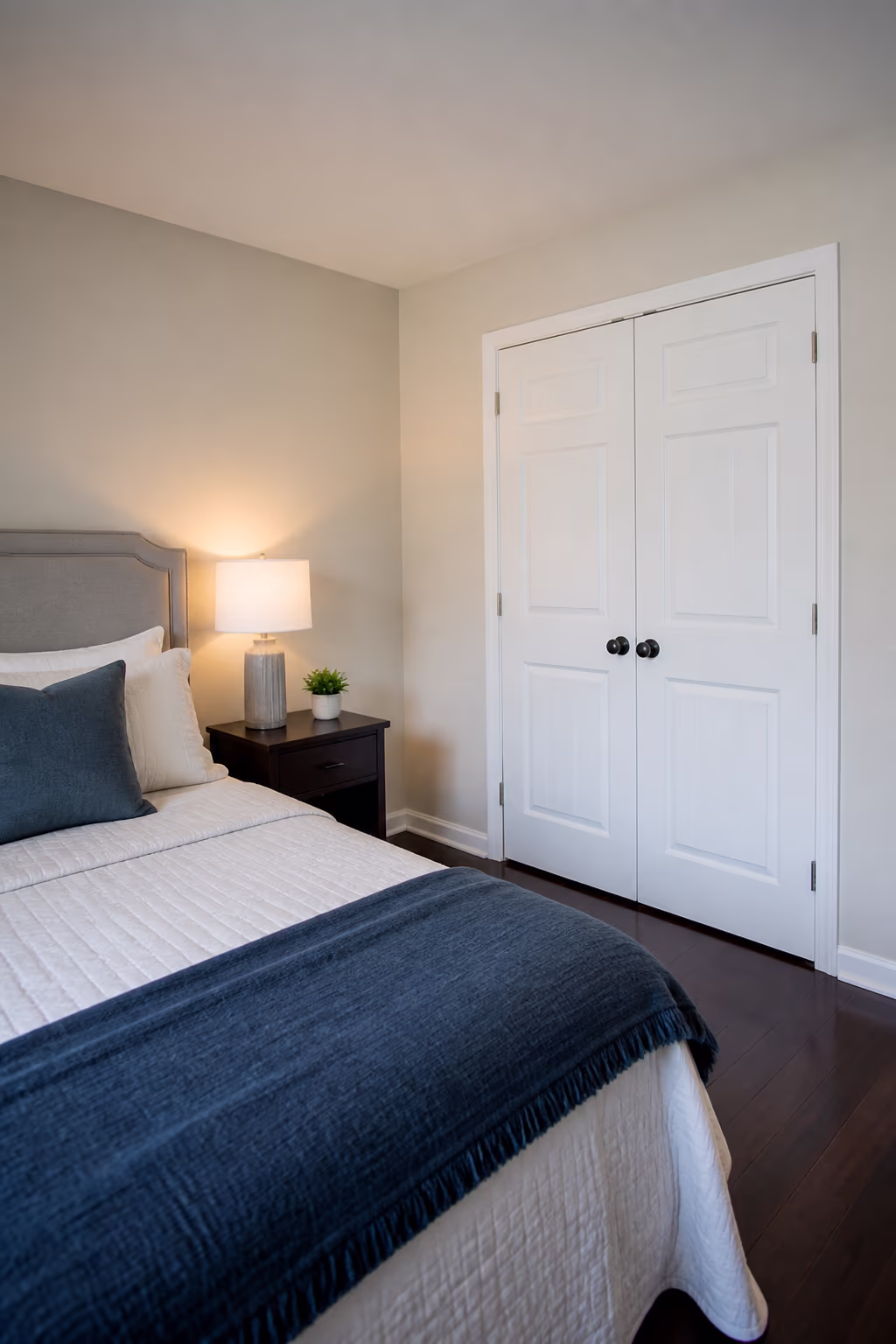 A portrait of a tidy Ottawa bedroom with a clear nightstand, neatly made bed and closed closet doors, capturing the calmer, easier-to-clean home that consistent decluttering habits create.