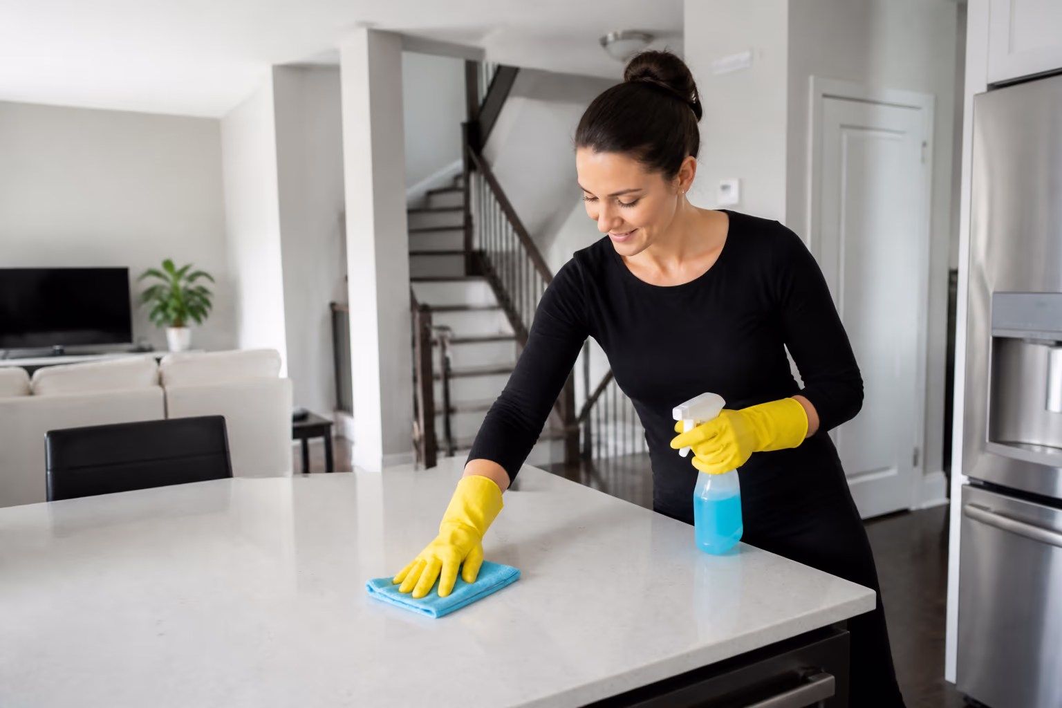 Cleaner detailing a kitchen island counter in a bright staged home
