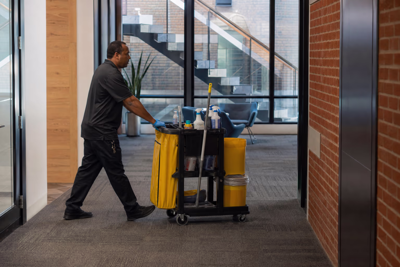 Cleaner guiding a janitorial cart through a shared building