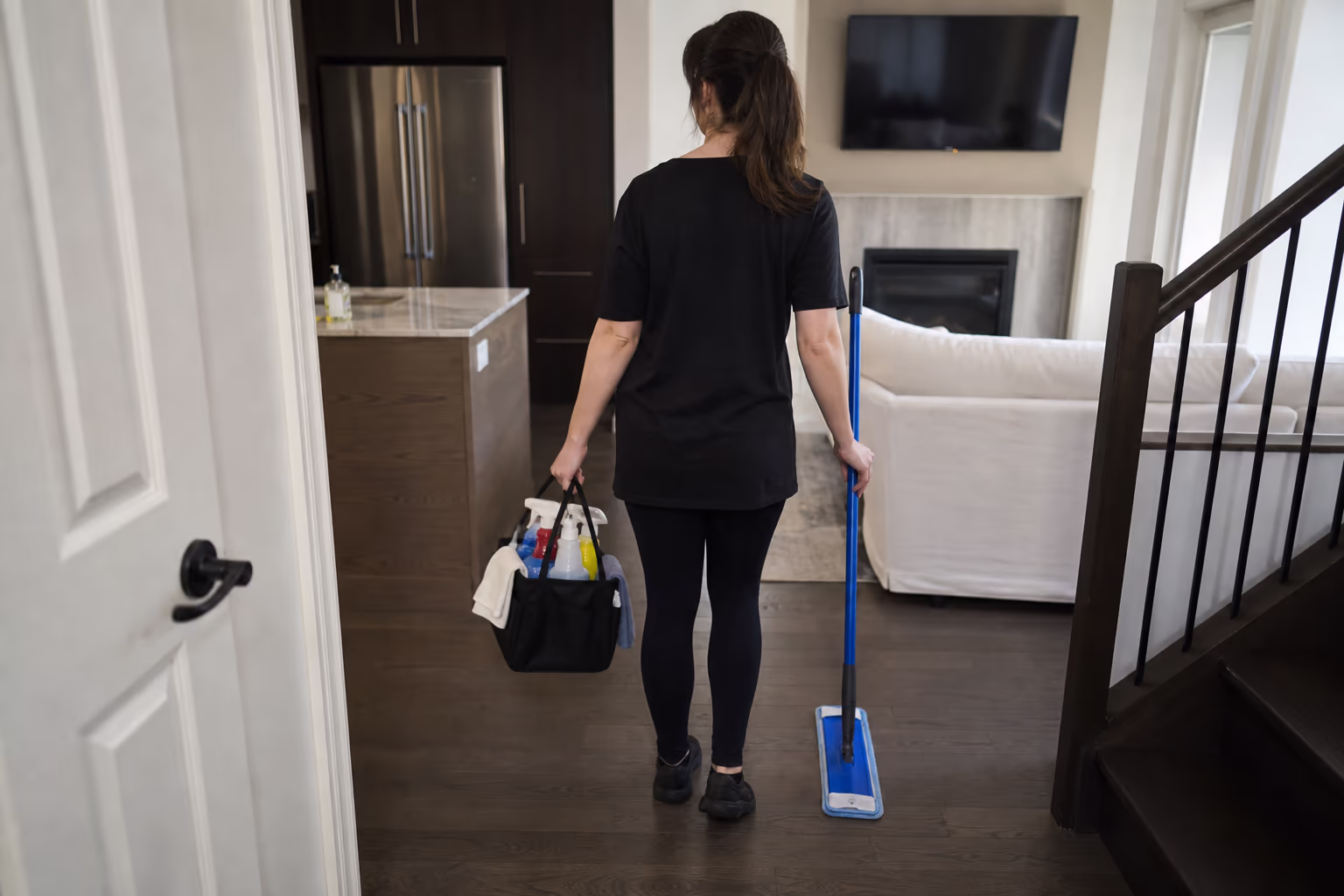 Cleaner carrying a supply bag and cleaning tools through a room