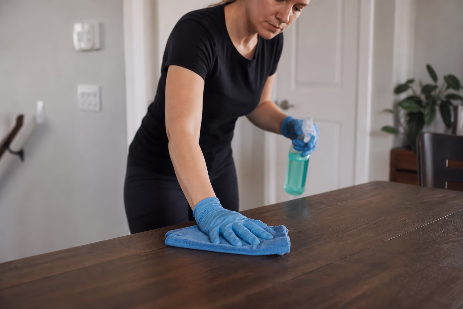 Gloved hands wiping a table with a cloth