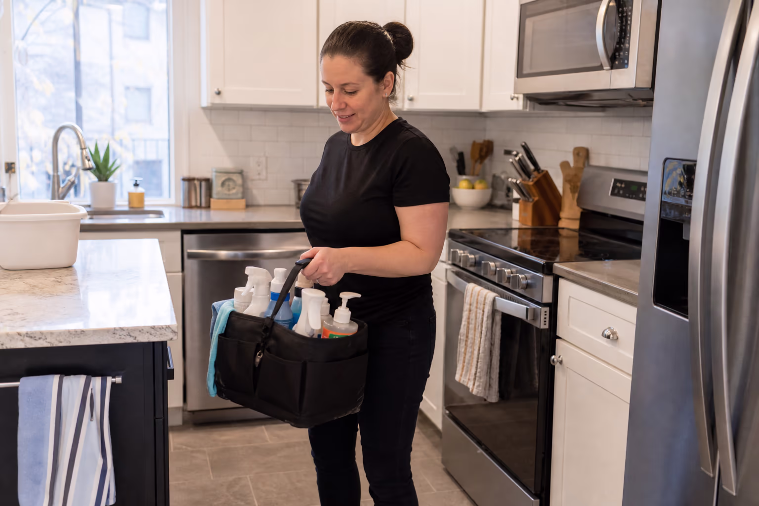 Cleaner holding a supply caddy in a kitchen