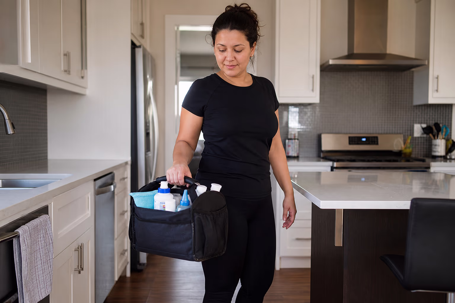 Cleaner holding a supply caddy in a kitchen