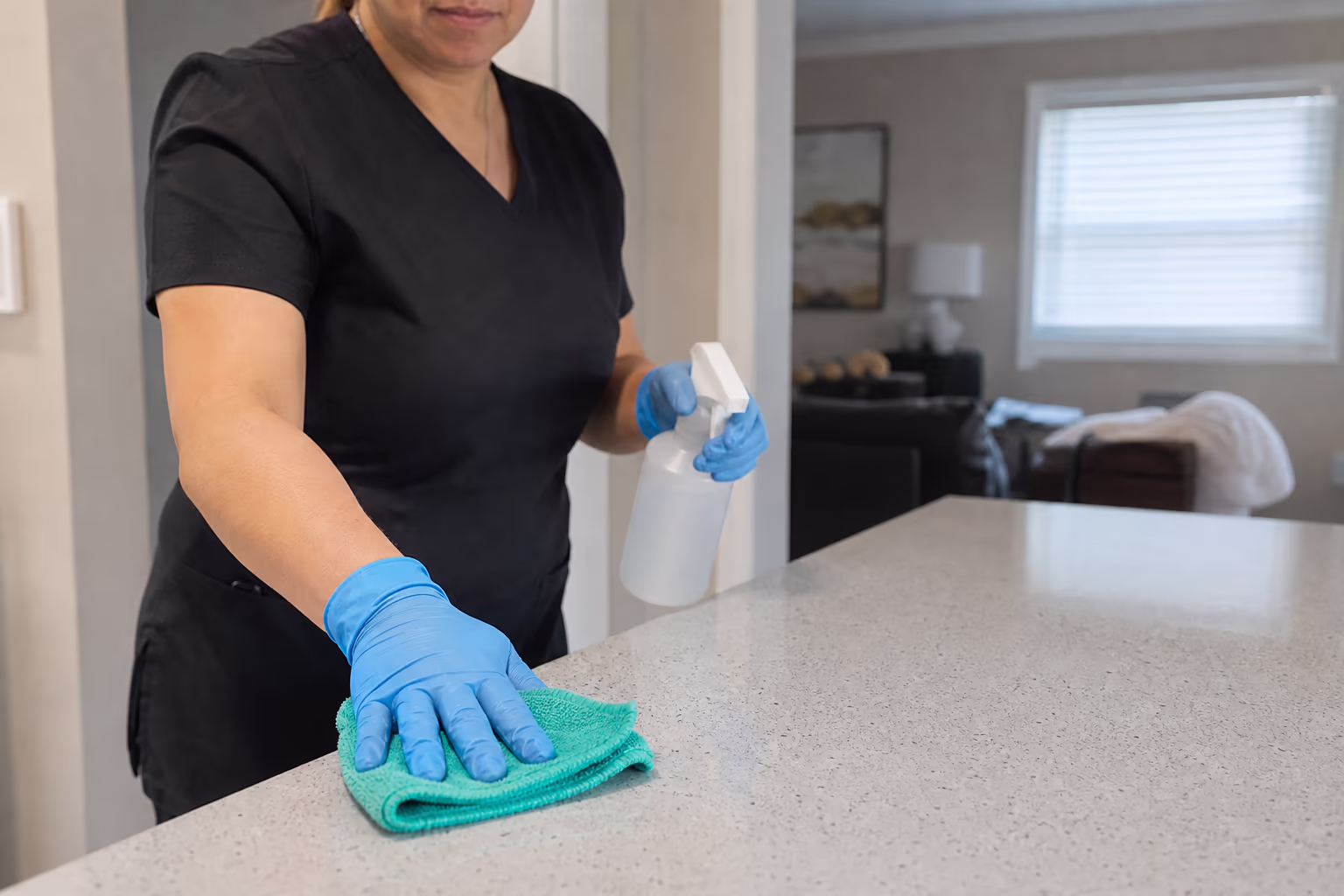 Gloved hands spraying and wiping a surface