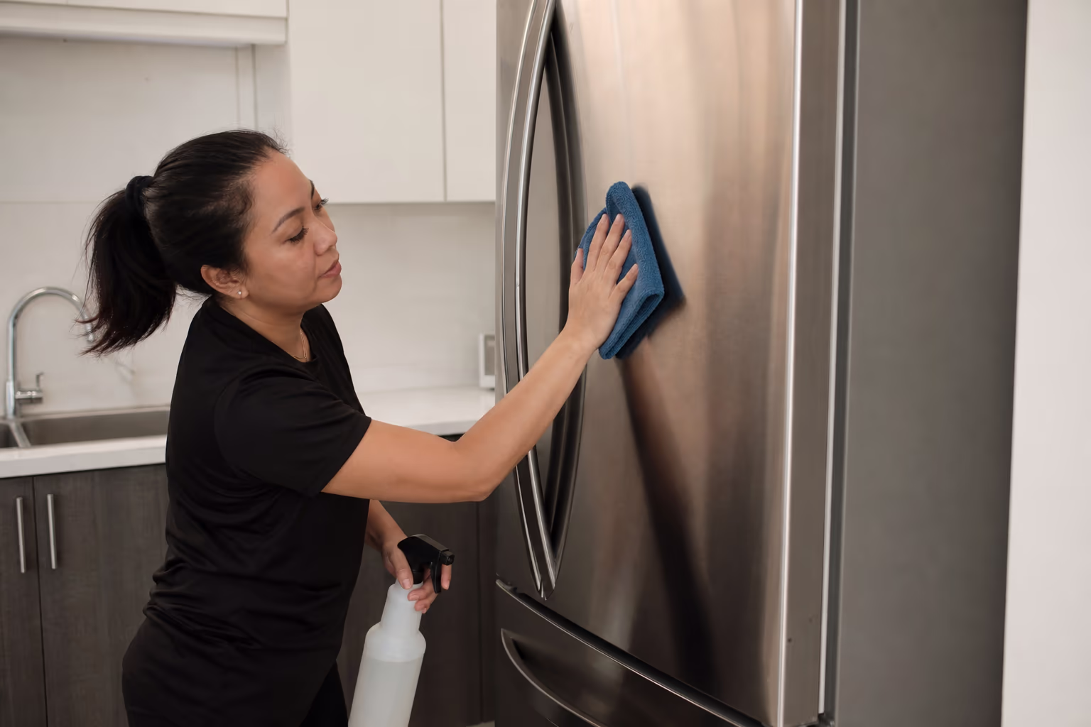 Gloved hands cleaning a kitchen counter and sink during a move clean