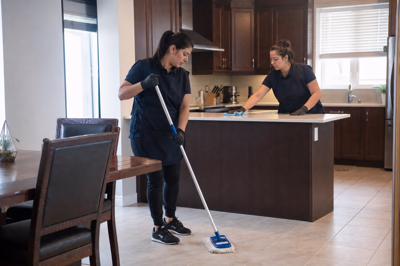 Three cleaners in aprons inside a bright room